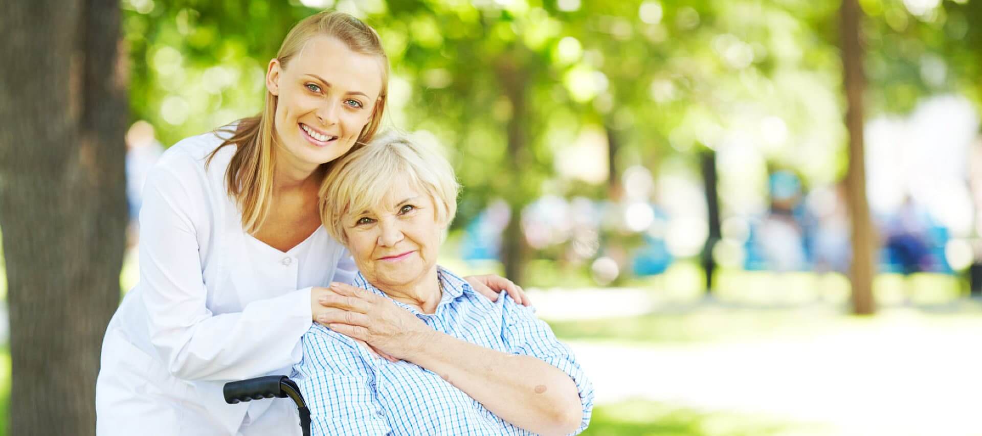 caregiver and senior woman in wheelchair smiling